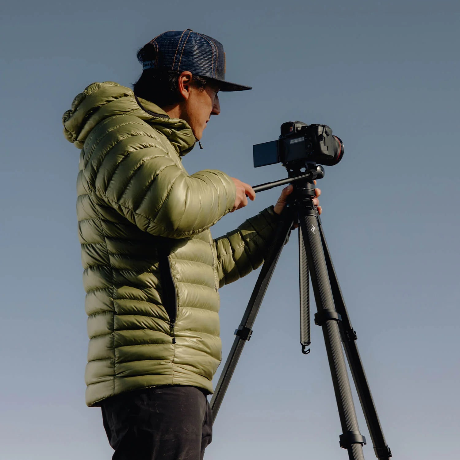 Photo of a man adjusting his camera attached to a tripod